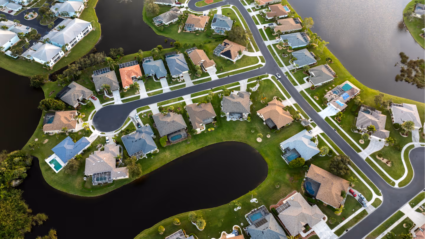 Architectural blueprint with a yellow hard hat, a level, a metal compass, a transparent protractor, and two pens on top.