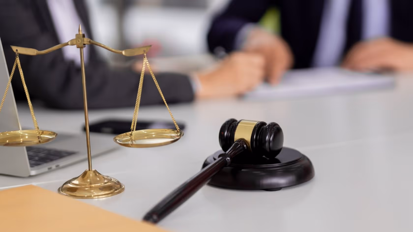 Smiling adult woman with glasses wearing a yellow sweater, pointing at a whiteboard with multicolored sticky notes.