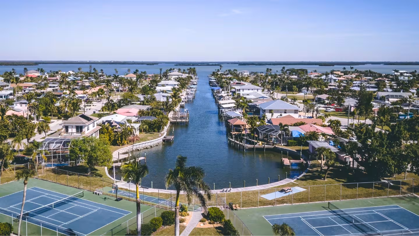 City skyline at sunset with a river and bridge in the foreground under a clear blue sky.