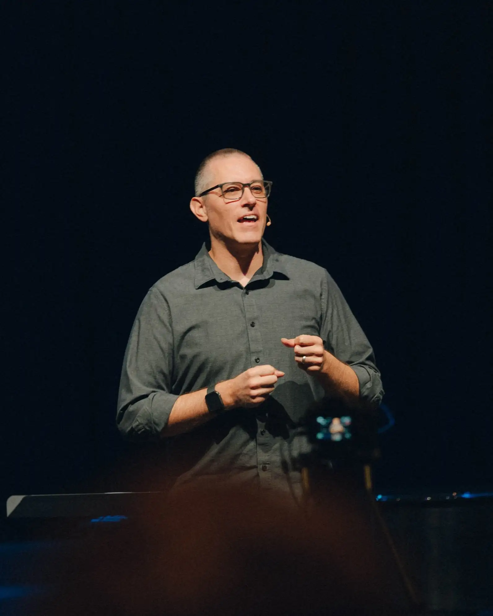 Lead pastor speaking on stage with a microphone headset.