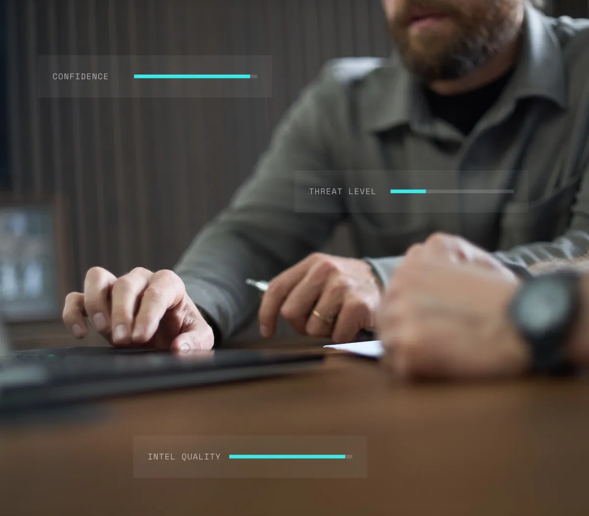 Man using computer keyboard with digital overlays showing confidence, threat level, and intel quality bars.