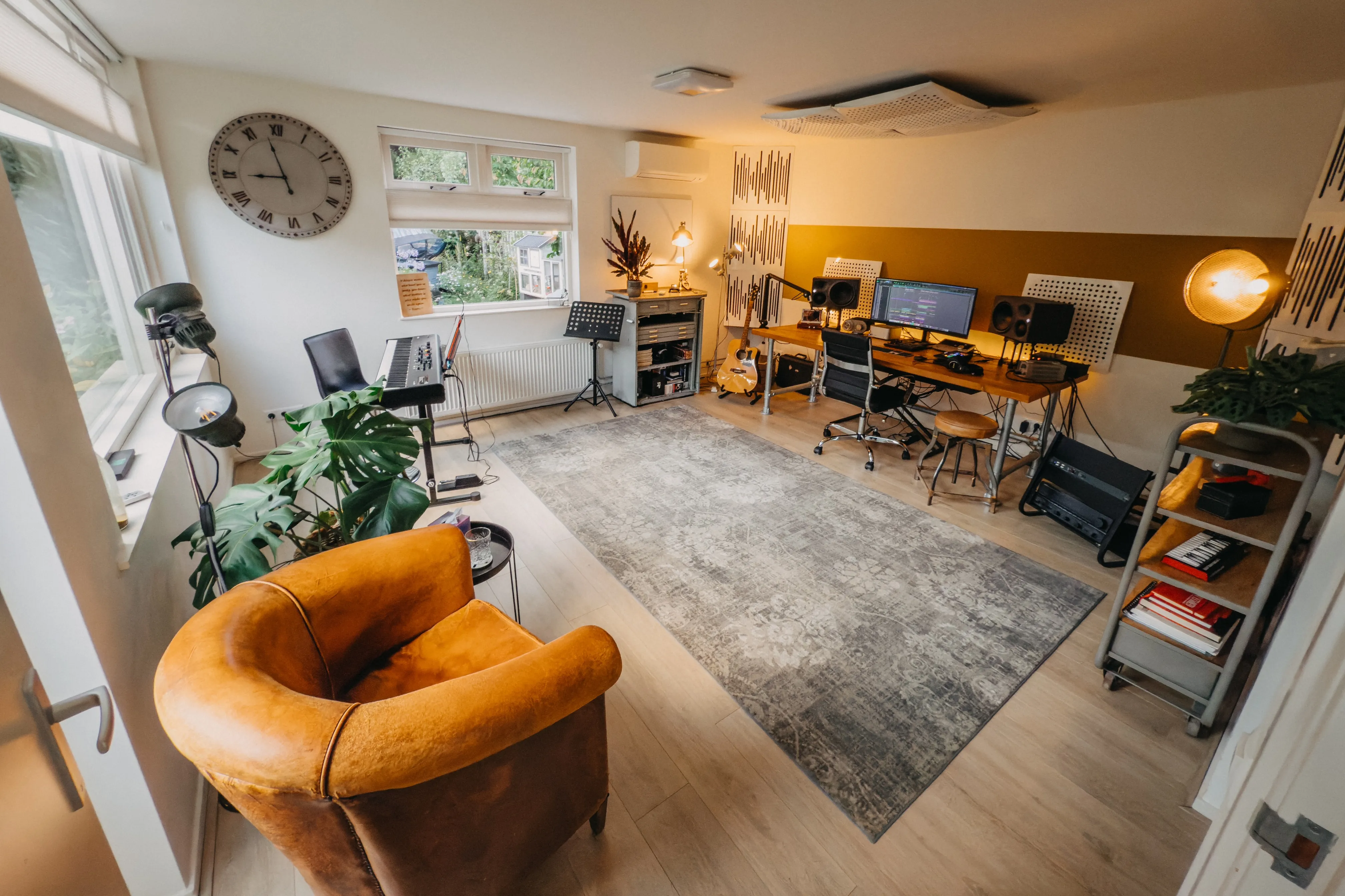 De studio van Adam Music, Harderwijk. Een mooie, ruime studio met een leren stoel, vloerkleed, bureau en studioapparatuur.