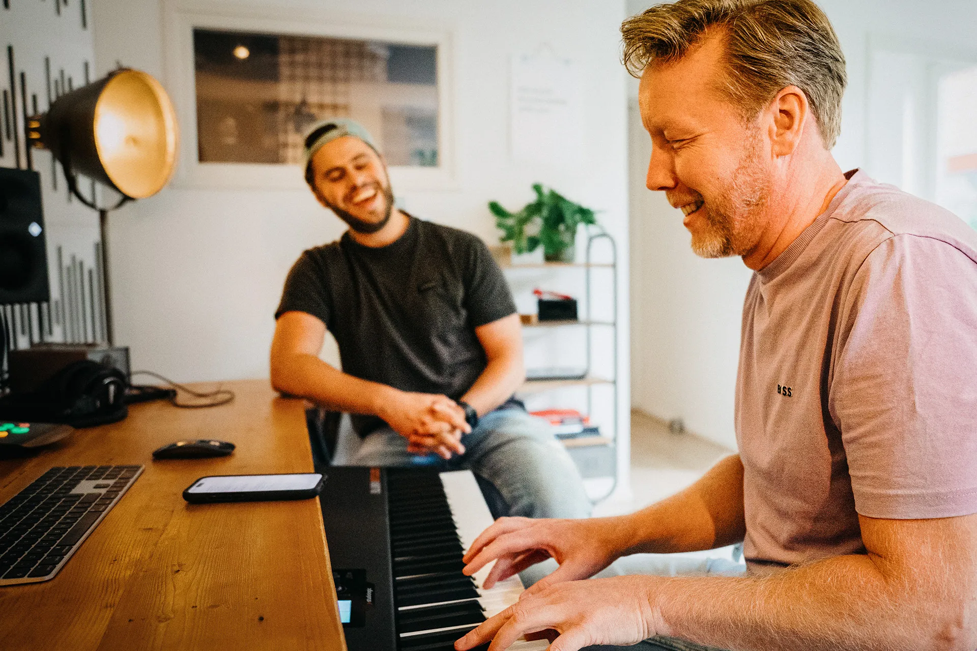 Adam Dekker in zijn studio Adam Music te Harderwijk, samen met de artiest waar hij tekst en muziek voor schrijft. Adam Dekker zit achter de piano.