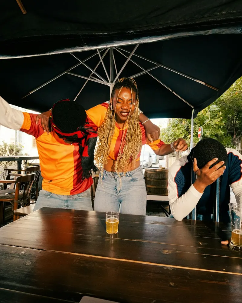 Friends celebrating a big moment while watching a game at an outdoor bar