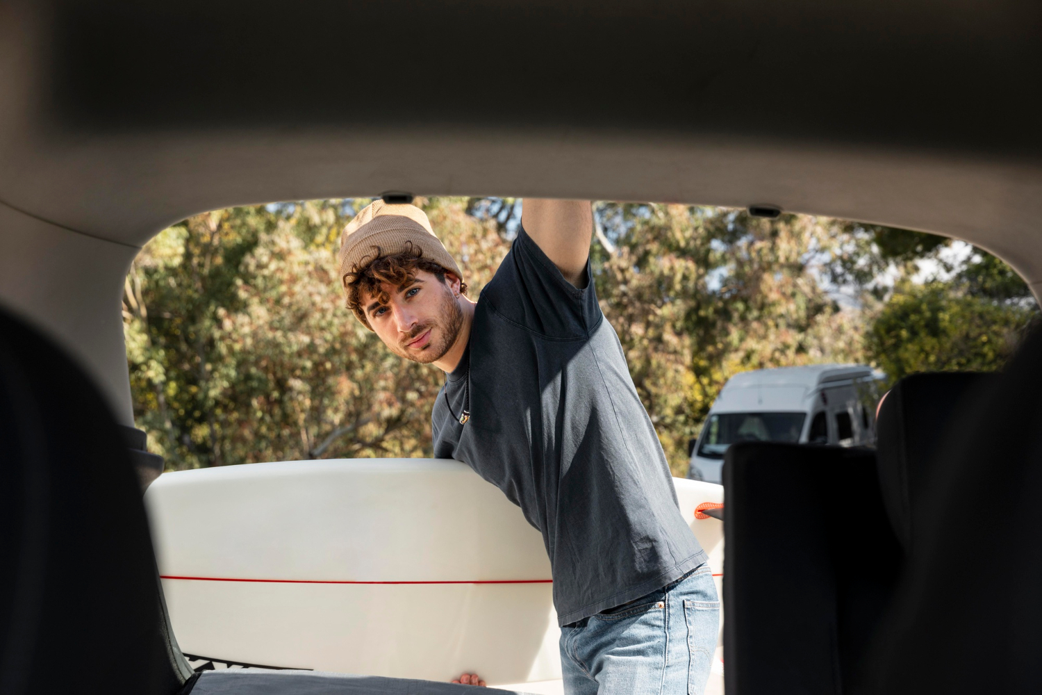 Man loading a surfboard into the back of his car, representing travel freedom and peace of mind with a vehicle warranty subscription.