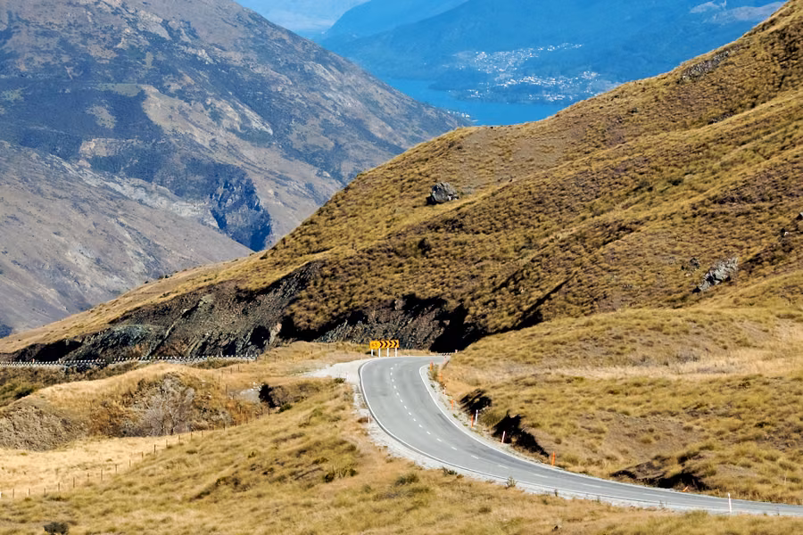 Crown Range Road hairpin above the Wakatipu Basin with snowy ranges behind