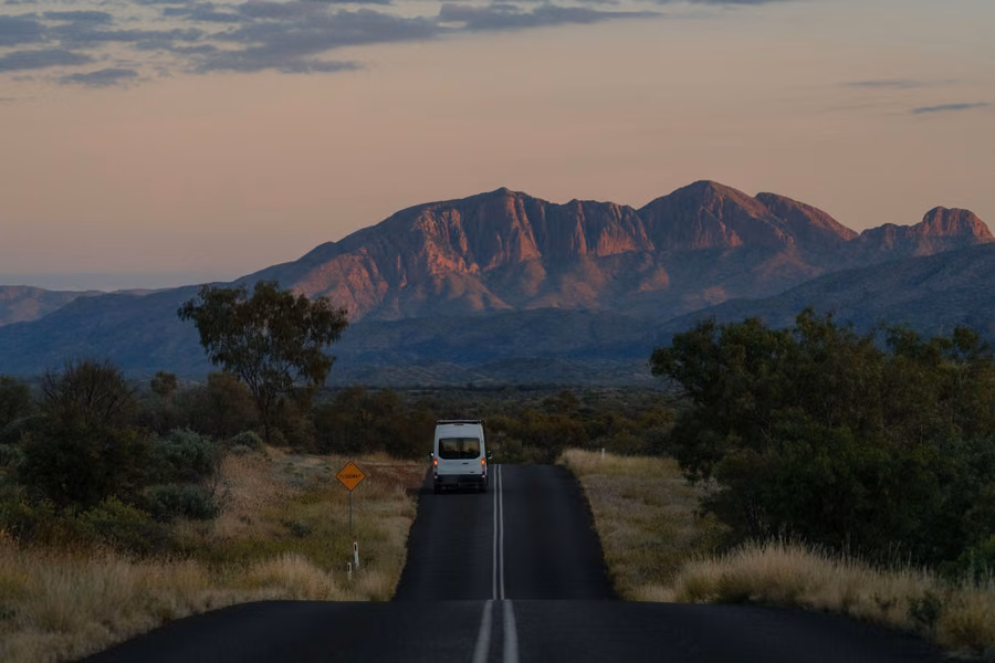 White van on the road towards the West MacDonnell Ranges in evening light near Alice Springs