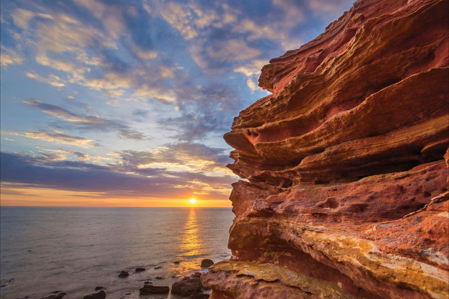 Layered red sandstone cliffs at Gantheaume Point with the sun setting over the Indian Ocean