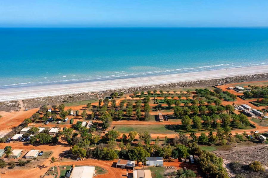 Aerial view of Eighty Mile Beach Caravan Park's shaded sites beside a long white beach and turquoise sea