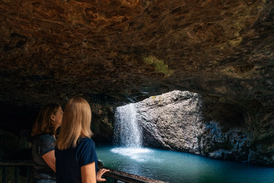 Visitors watching a waterfall pour through the cave roof at Natural Bridge in Springbrook National Park