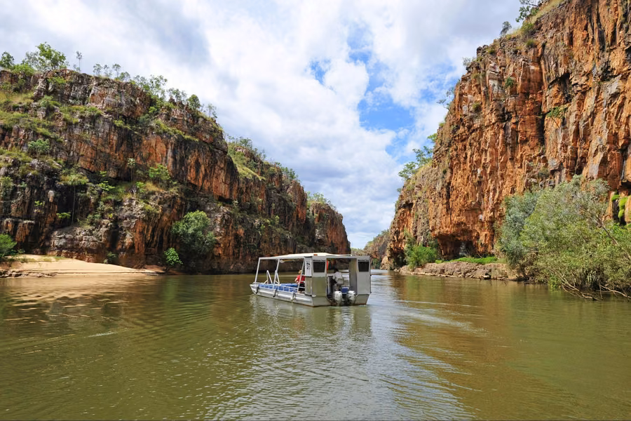 Tour boat cruising between towering red sandstone cliffs on the river in Nitmiluk (Katherine) Gorge
