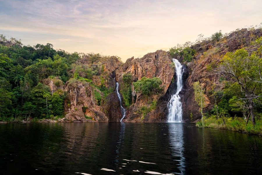 Twin waterfalls of Wangi Falls tumbling down red rock cliffs into a still plunge pool in Litchfield National Park