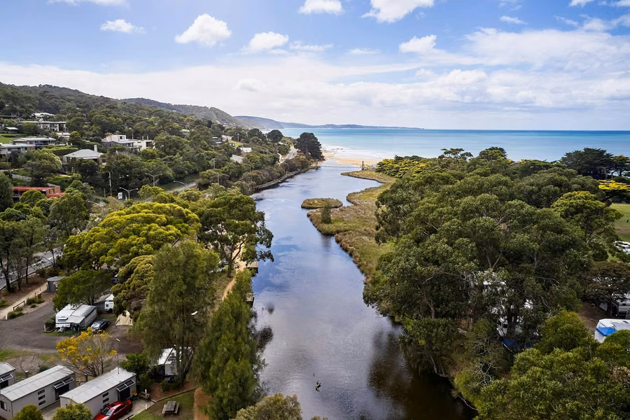 Aerial view of the Erskine River winding past riverside cabins and caravan sites to the beach at Lorne