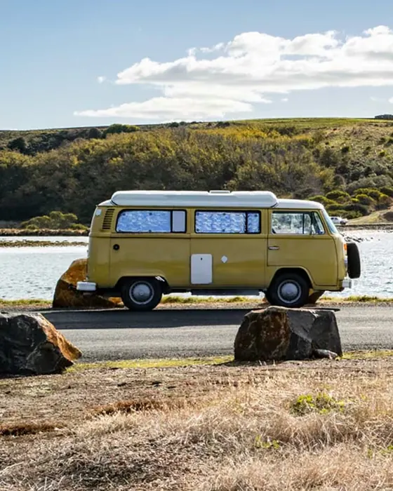 Vintage campervan parked beside the water on the Tasmanian coast