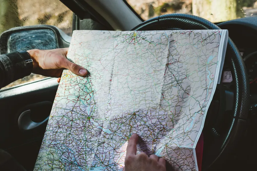 Traveller reading a paper road map at the steering wheel