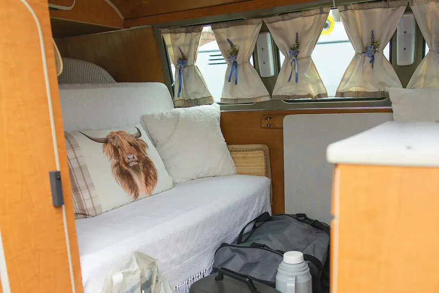 Inside a campervan with a bench seat, curtained windows and travel bags
