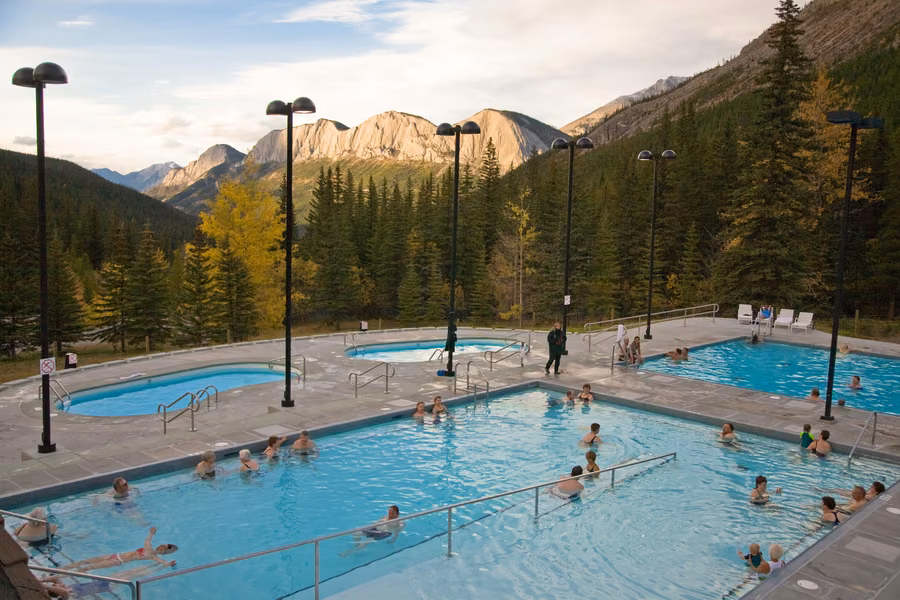 Bathers in the outdoor pools at Miette Hot Springs, surrounded by forest and rocky mountain peaks