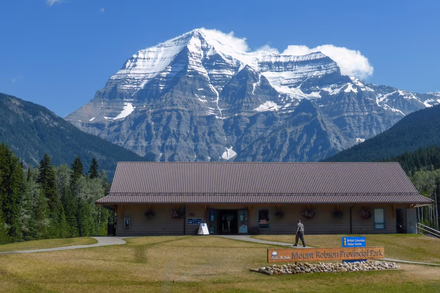 Snow-capped Mount Robson rising behind the Mount Robson Provincial Park visitor centre on a sunny day