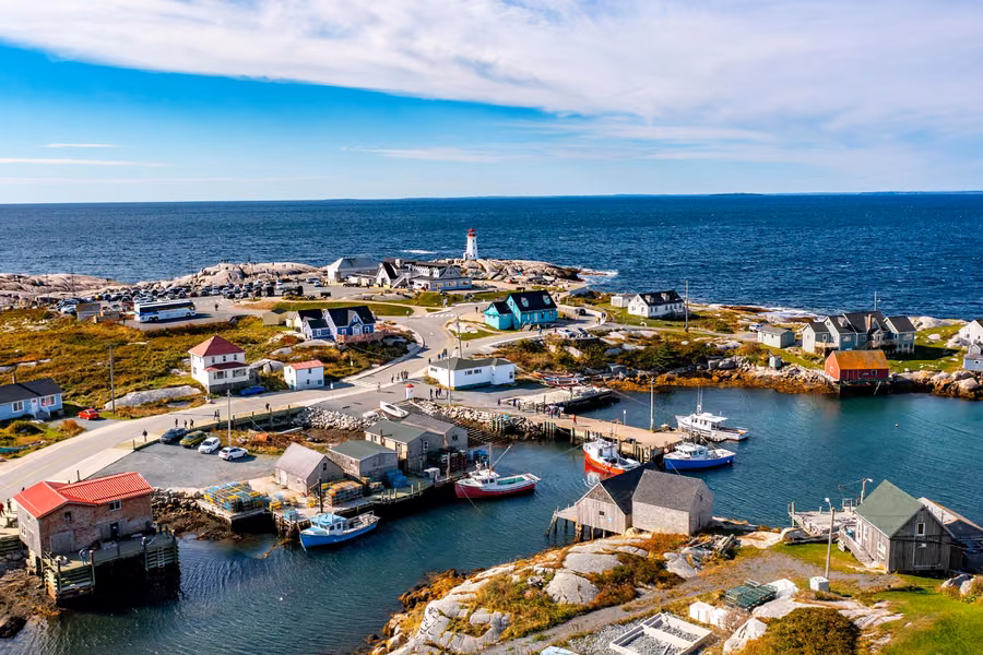 Aerial view of Peggy's Cove village, with fishing boats in the harbour and the lighthouse in the distance