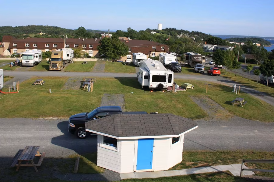 RVs and trailers on grassy sites at Lunenburg RV Park & Campground, with the harbour beyond