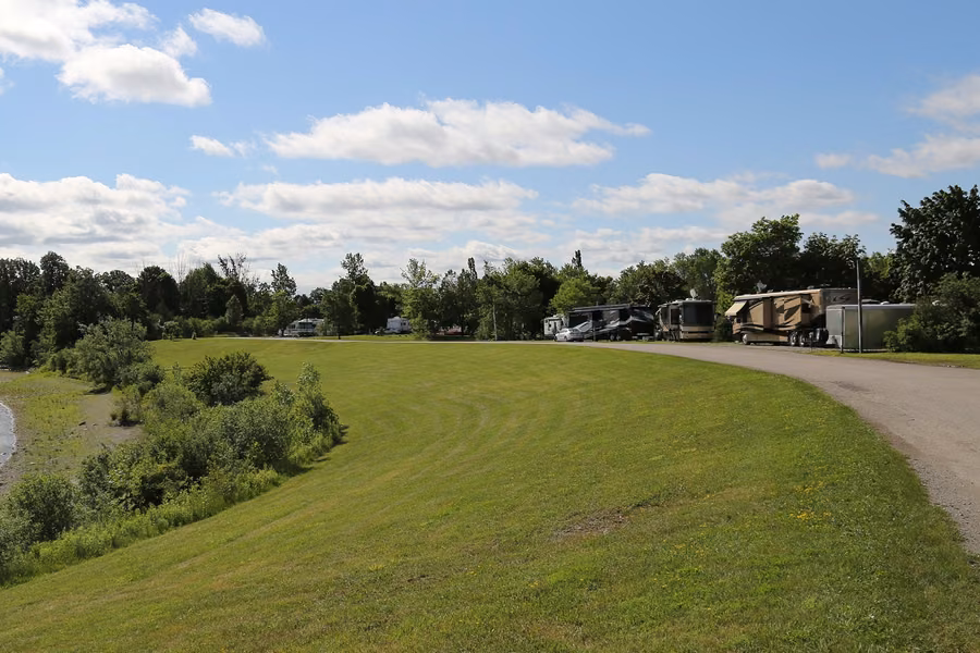 Grassy bank sloping down to the water at Indian Line Campground, with RVs and trailers parked along the campground road