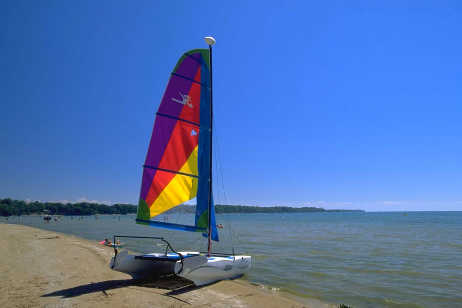 Colourful catamaran pulled up on the sand beside the long Lake Ontario beach at Sandbanks Provincial Park