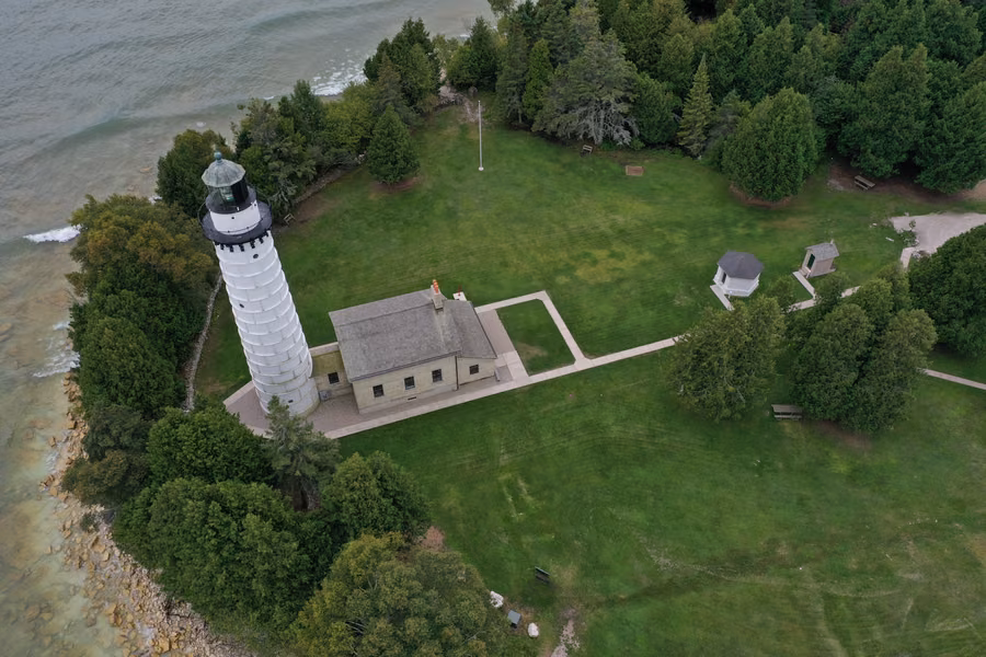Aerial view of the white Cana Island Lighthouse and keeper's house among cedars on the Lake Michigan shore in Door County