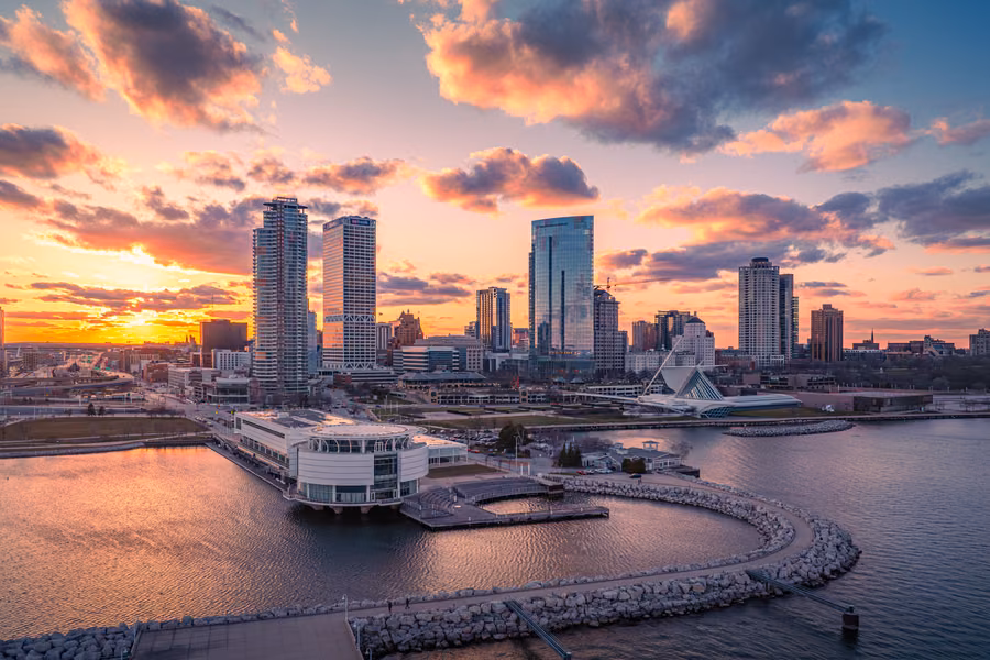 Milwaukee skyline at sunset above the Lake Michigan harbour, with Discovery World and the Milwaukee Art Museum's winged pavilion