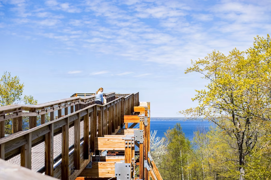Visitors on the timber ramp of Eagle Tower above spring treetops and the blue waters of Green Bay at Peninsula State Park