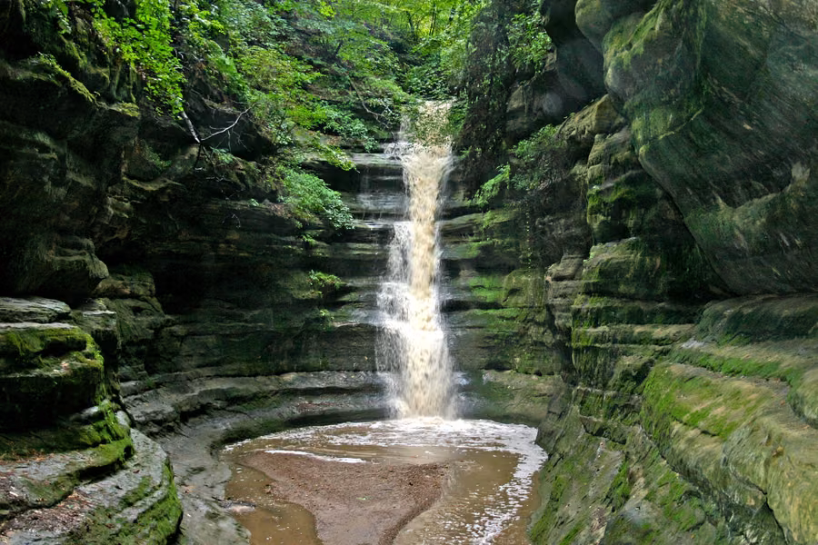 Waterfall pouring into a mossy sandstone canyon at French Canyon in Starved Rock State Park