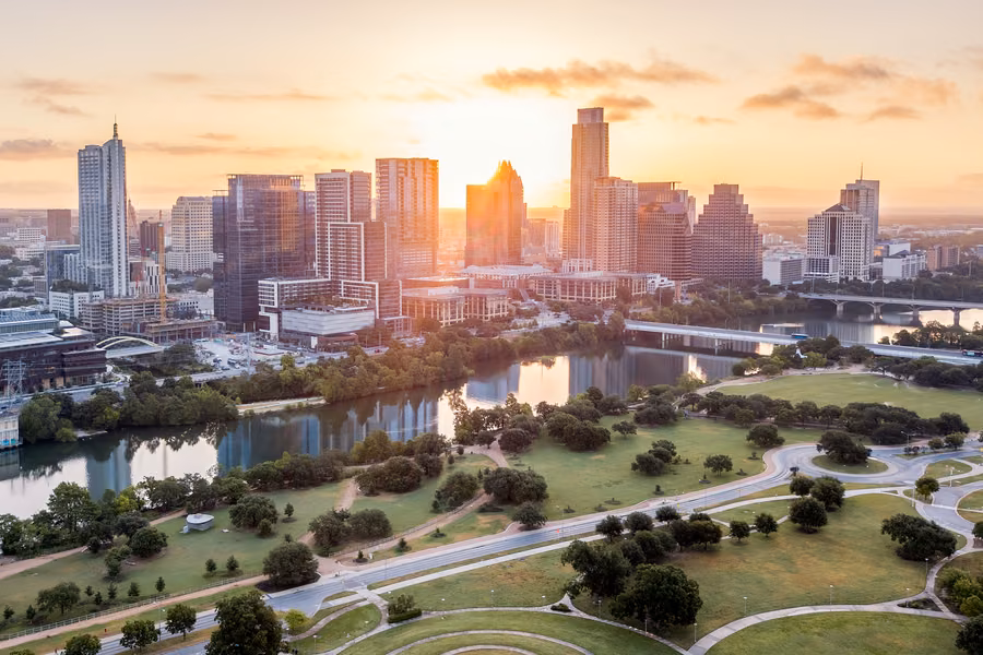 Aerial view of the Austin skyline at golden hour above Lady Bird Lake and the parkland on its south bank