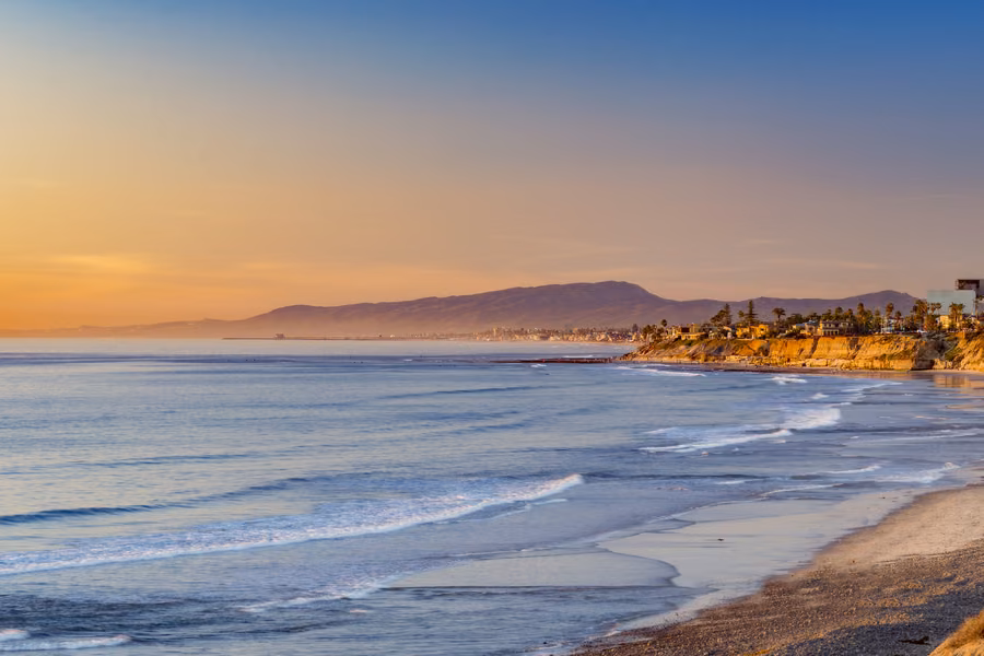 Waves rolling onto South Carlsbad State Beach below sandstone bluffs at sunset