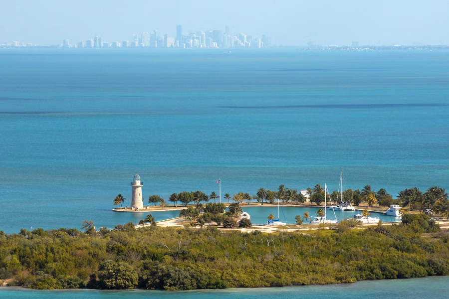 Boca Chita Key lighthouse and harbour ringed by palms in turquoise water, with the Miami skyline on the horizon, in Biscayne National Park