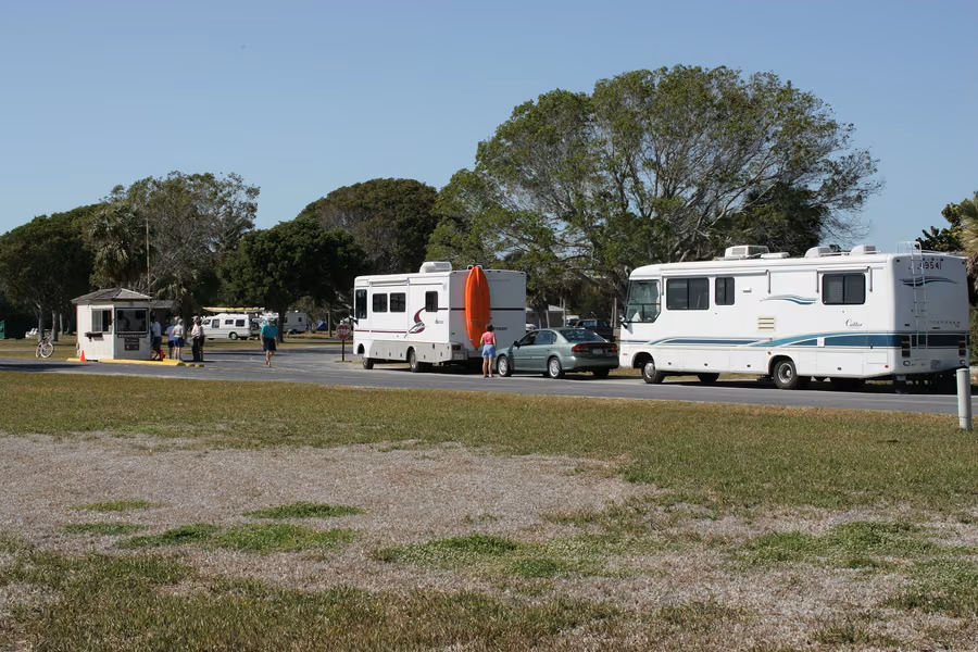Two motorhomes and a car lined up on the road beside the entrance kiosk at Flamingo Campground in Everglades National Park