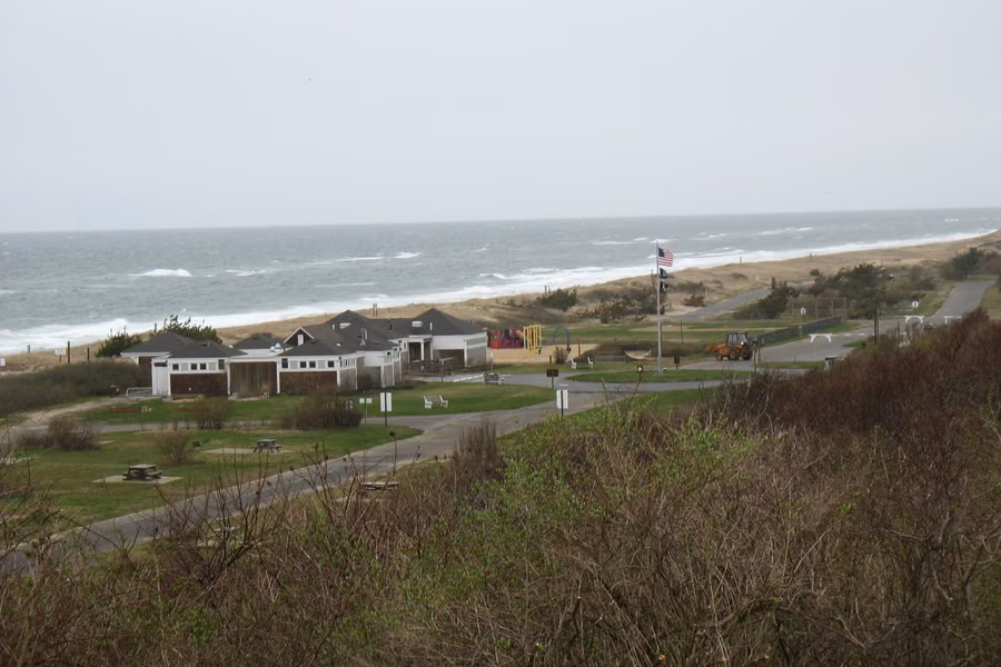Picnic lawns and park buildings above the ocean beach at Hither Hills State Park on an overcast day