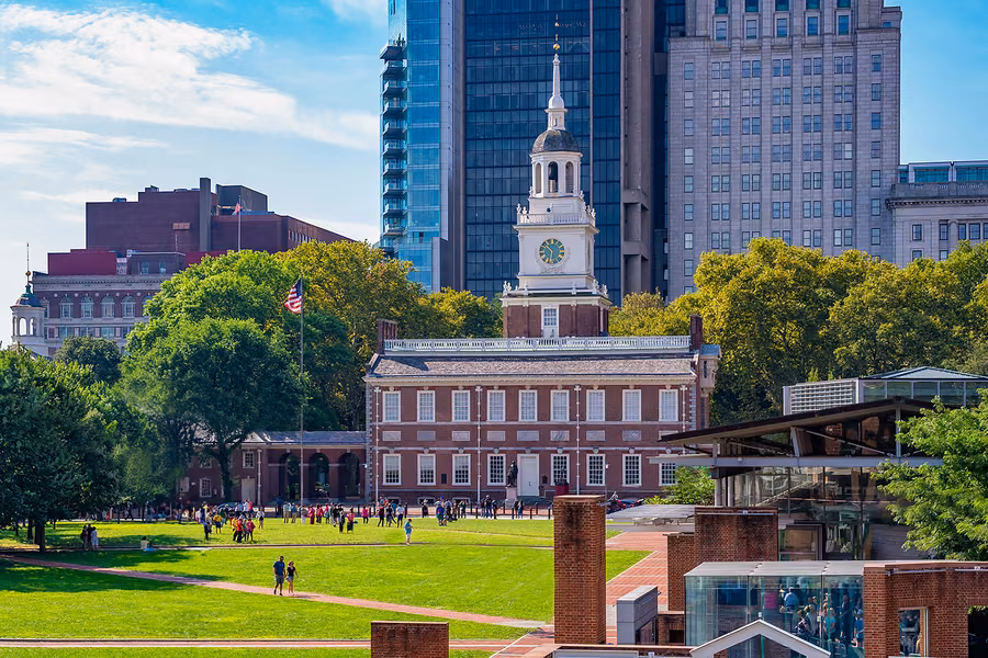 Independence Hall and its clock tower behind the lawns of Independence Mall, with city towers rising behind