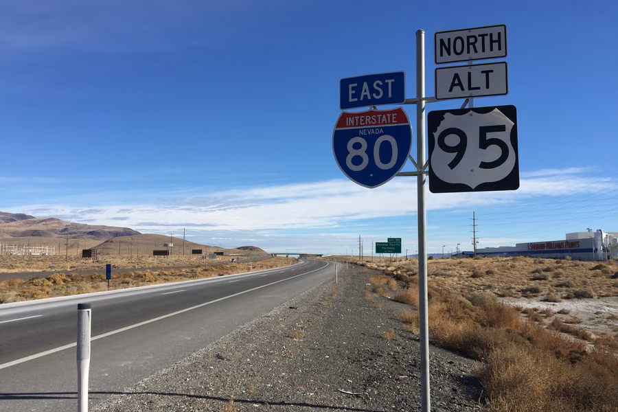 Interstate 80 and US 95 Alternate road signs beside the highway near Fernley, Nevada, with desert hills behind