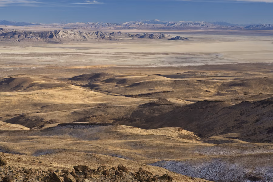 Rolling golden hills above the flat pale Black Rock Desert playa stretching to distant ranges