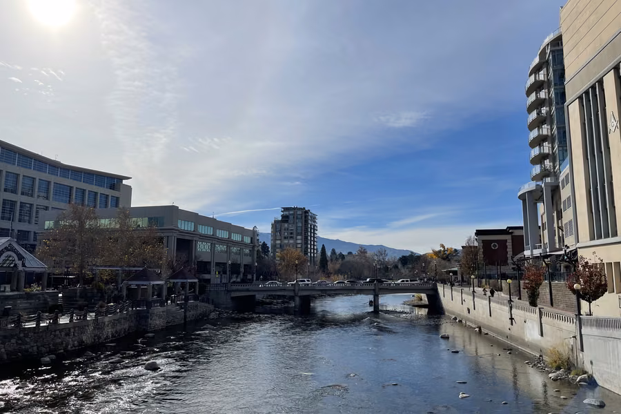 The Truckee River flowing through downtown Reno beneath a footbridge, with hotel and office buildings on both banks
