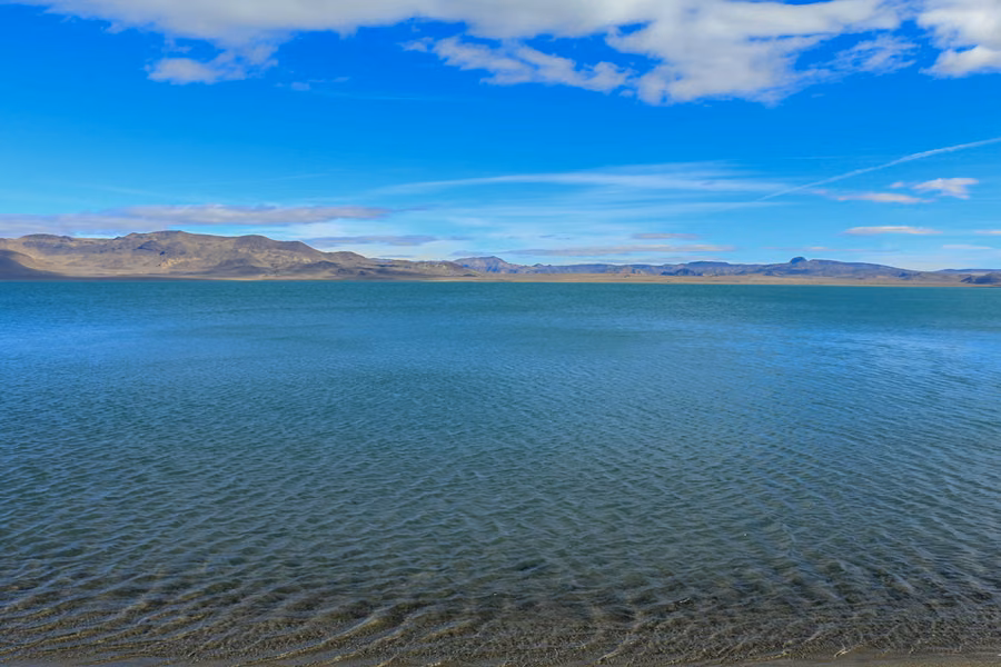 Turquoise water of Pyramid Lake with desert mountains along the far shore under a blue sky