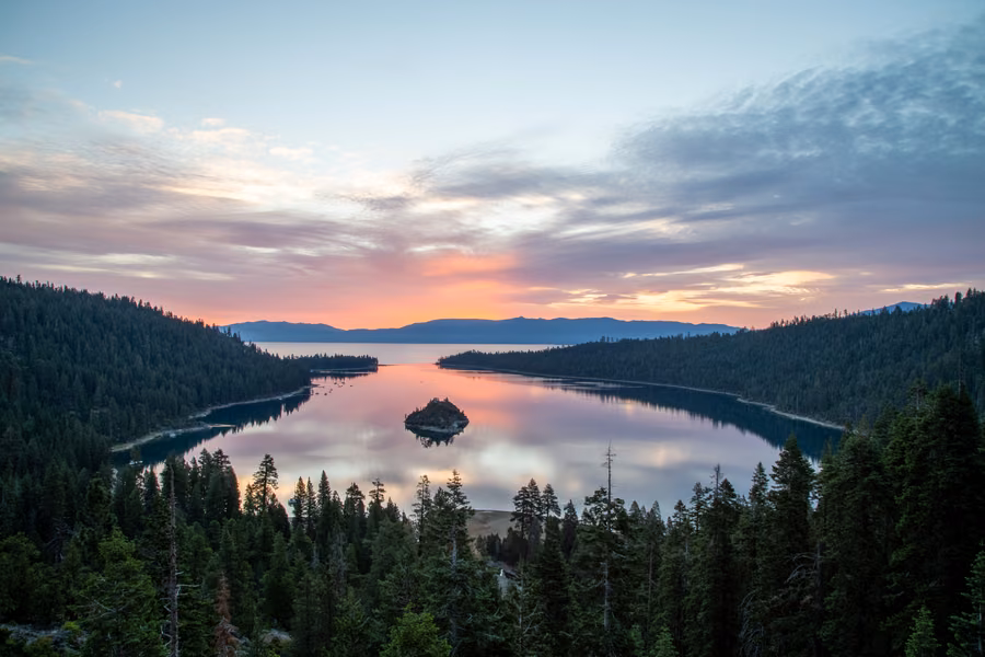 Emerald Bay and Fannette Island at sunrise, with pine forest around a calm blue lake