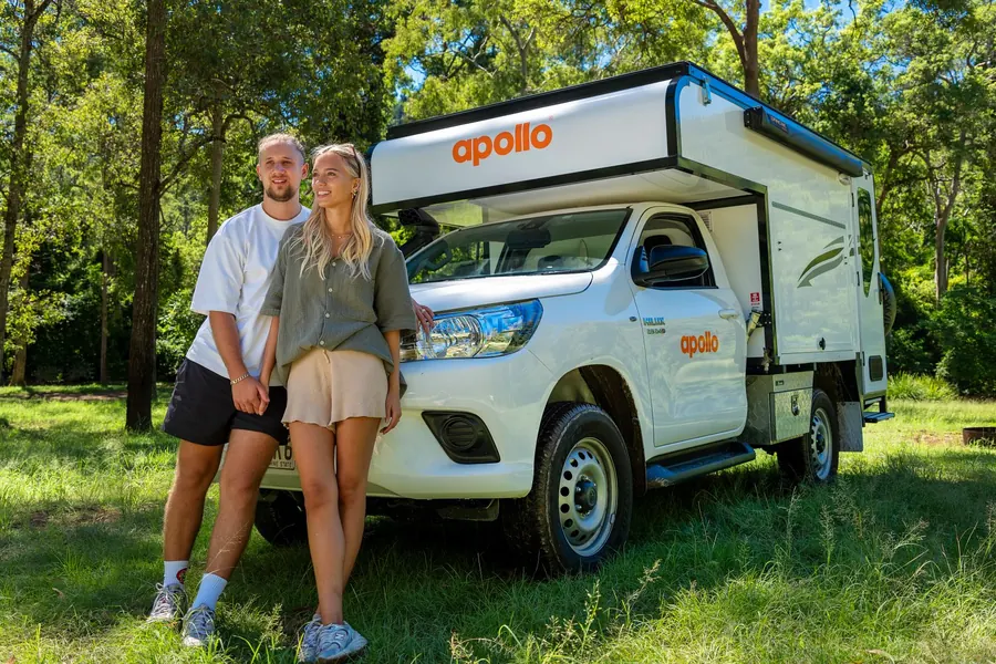 Couple standing beside an Apollo Adventure Camper 4WD in bushland