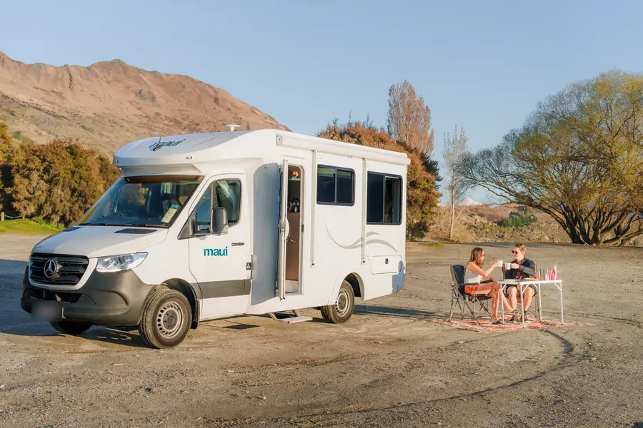 Couple having coffee beside a maui Cascade motorhome near Lake Wanaka, New Zealand