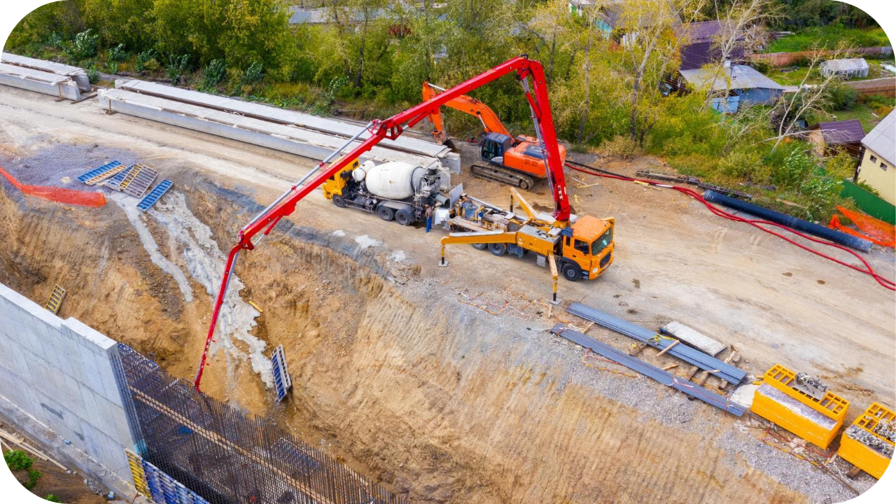 concrete pump truck with extended boom pouring concrete on a highway construction project site.