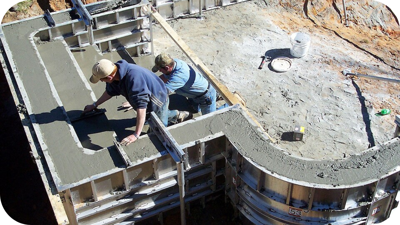 Two builders smoothing wet concrete on curved wall formwork, highlighting small job concrete pumping for garden edging and landscaping projects in residential settings.