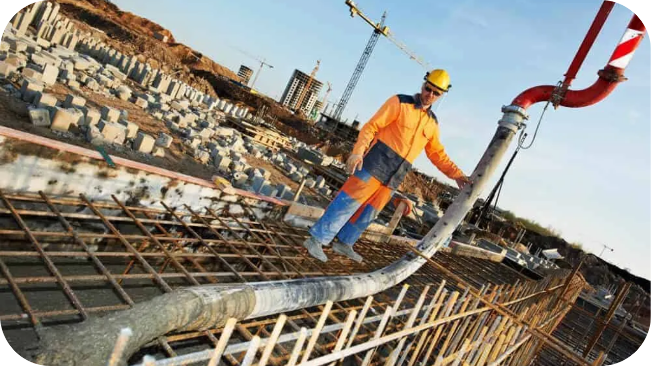 Construction worker guiding concrete pump hose to pour concrete on reinforced building structure.