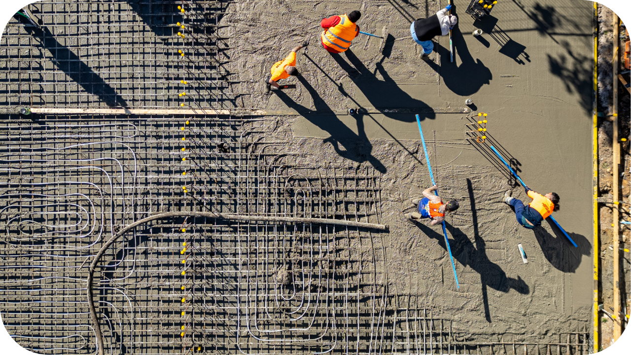 Aerial view of workers using a line pump to pour concrete over a reinforced foundation in Melbourne.