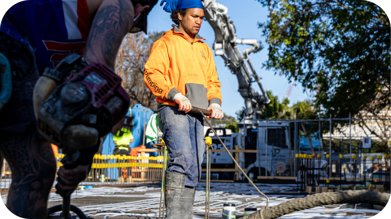 Construction worker operating a concrete hose connected to a boom pump on a Melbourne building site.