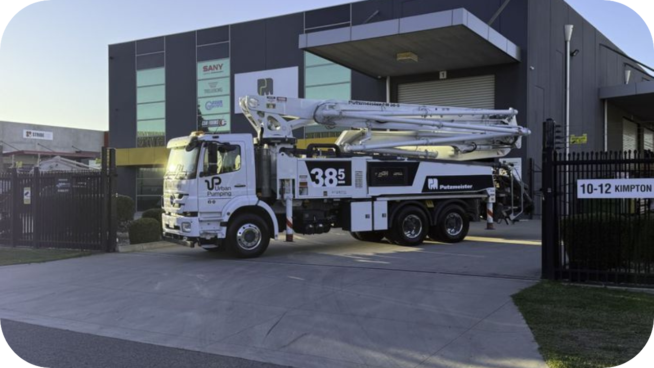 Urban Pumping boom pump truck parked outside company warehouse, ready for concrete pumping and high-rise services.