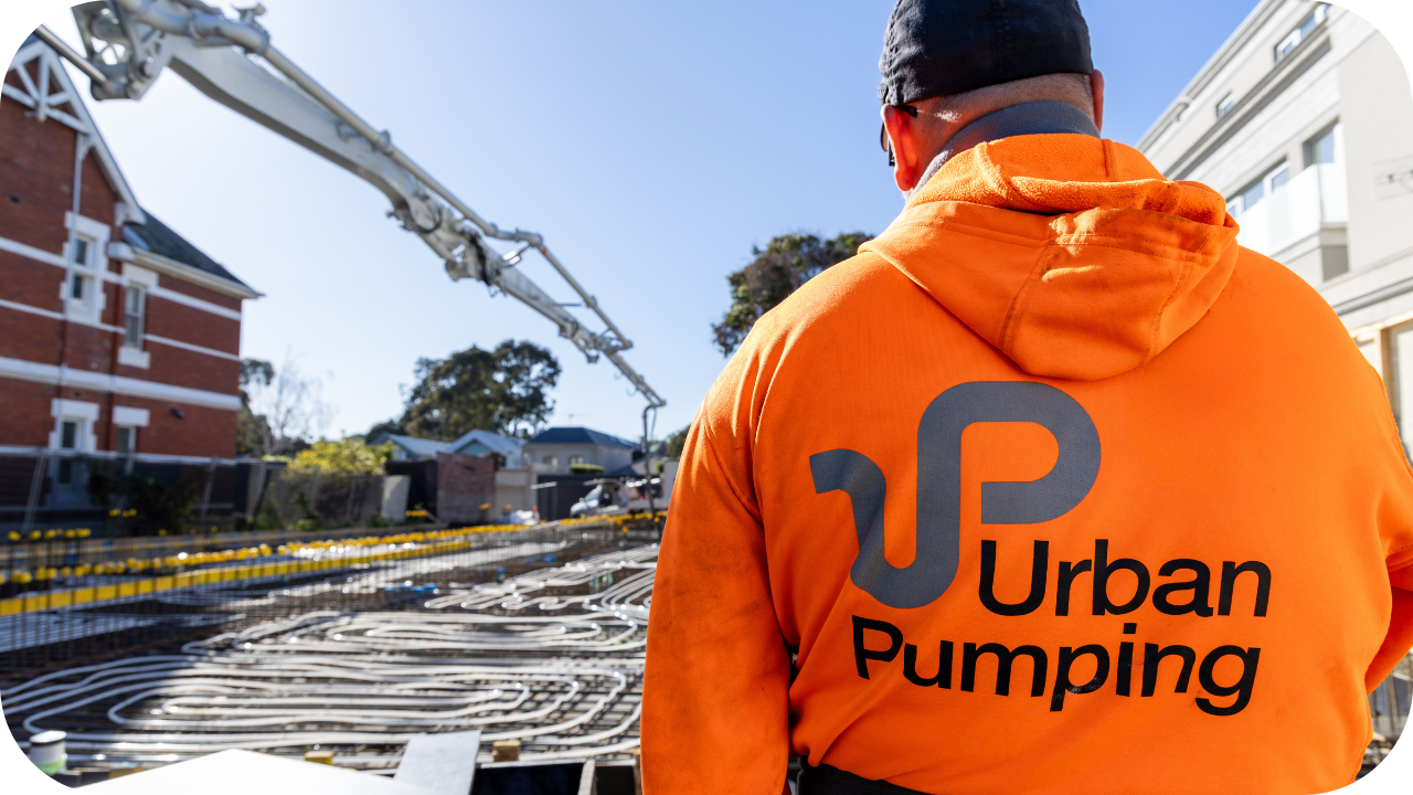 Urban Pumping worker in an orange hoodie overseeing a concrete pour on a residential construction site in Melbourne.